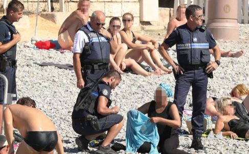 Policías franceses poniendo una multa a la mujer que llevaba un burkini en Niza.